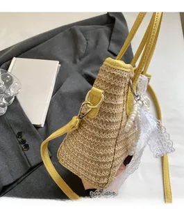 Detail of straw bucket bag with lemon yellow leather trim and lace pearl charm