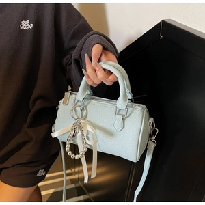 Détail du sac cylindre bleu clair en cuir grainé avec pendentif nœud élégant