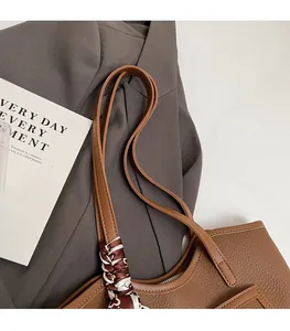 Detail of durable brown leather tote shoulder straps with decorative printed silk scarf