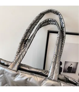 Close-up of silver quilted tote bag featuring metallic fabric and padded shoulder straps