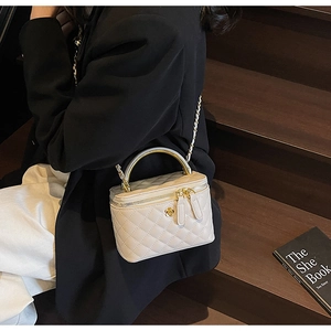Detail of a quilted crossbody bag with golden handle and chain strap on wooden stairs