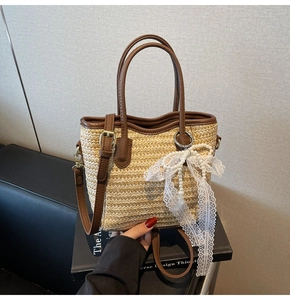 Detail of straw woven bucket bag featuring pearl charms and brown leather trim accents