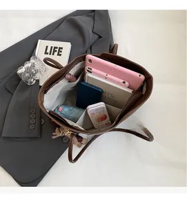 Top view of large brown tote bag interior with multiple compartments and a plush bear charm