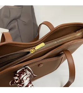 Close-up of smooth golden zipper and lychee pattern leather on brown tote bag