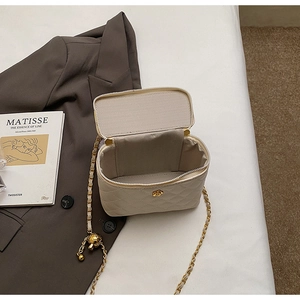 Detailed view of quilted beige handbag featuring a gold rose clasp and chain strap
