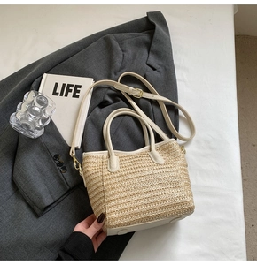 Detailed top view of a straw bucket bag with white faux leather trim and golden hardware