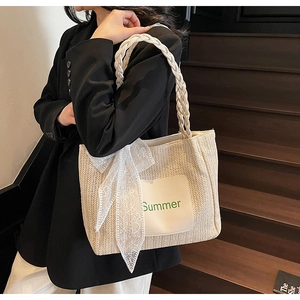 Detail of straw tote bag featuring white lace bow and Summer leather patch detail