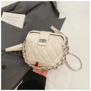 Detail of quilted beige crossbody bag with silver chunky chain and metal turn-lock closure