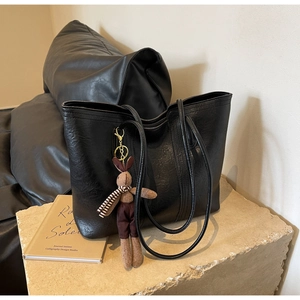 Detail of black tote bag with vintage pleated texture and cute rabbit plush pendant