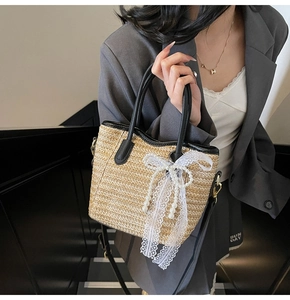 Detail of straw bucket bag with white lace bow, pearl accents and black leather handles