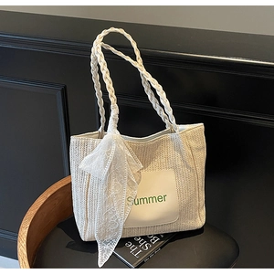 Close-up of beige straw tote bag with Summer patch, rope handles and lace scarf detail