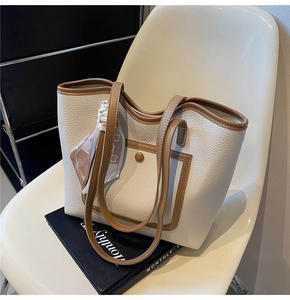 Detail of off-white lychee pattern tote bag with brown trim and decorative silk scarf handle