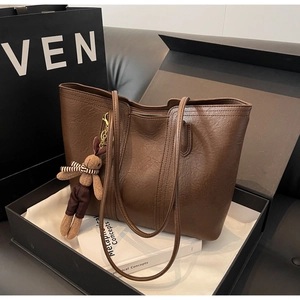 Detail of dark brown tote bag in a gift box featuring oil wax leather texture and rabbit charm