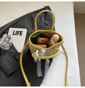 Interior storage view of mini woven straw bucket bag with yellow leather straps and pearls