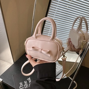 Detail of pink mini bag with bow accent, gold hardware and detachable shoulder strap