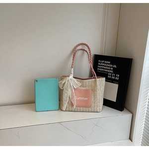 Detail of straw tote bag featuring Summer patch, pink handles and lace ribbon decoration