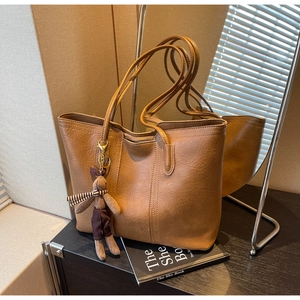 Detail of vintage brown leather tote bag featuring a cute plush bunny charm on the strap