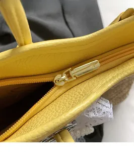 Detailed close-up of premium gold zipper and leather stitching on straw woven tote bag