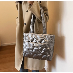 Detail view of the silver metallic puffer tote bag with chevron quilting and brand label