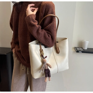 Detail of cream tote bag with brown straps and cute rabbit doll charm accessory