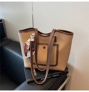 Detail of beige lychee grain tote bag with brown trim and decorative floral silk scarf