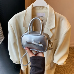 Detail of silver metallic mini bag featuring a decorative bow and round handles