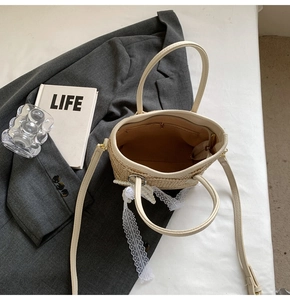 Top view of straw bucket bag showing pearl charms, lace trim, and inner zipper pocket