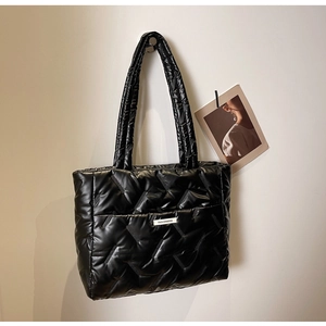 Close-up of black quilted tote bag hanging on a hook with a minimalist fashion aesthetic