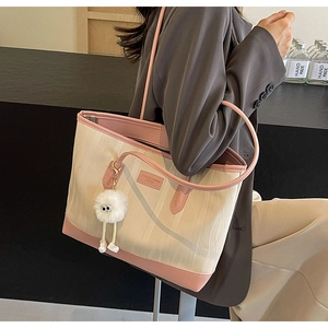 Detail of canvas tote bag with pink leather handles and plush charm accessory