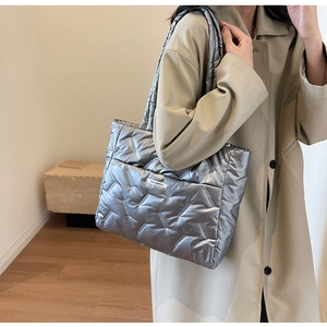 Detail of silver puffer tote bag with chevron quilting and fashion label on the front