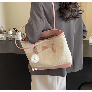 Close-up of contrast color tote bag featuring wave textures and a plush ball charm