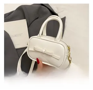 Close-up of white mini crossbody bag featuring a chic bow and gold hardware details