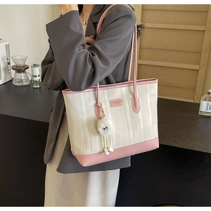Detail of color-block tote bag with vertical textures and pink leather trim and charm
