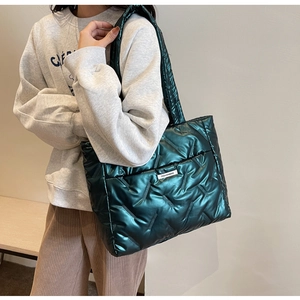 Close-up of dark green quilted tote bag with metallic finish and fashion label