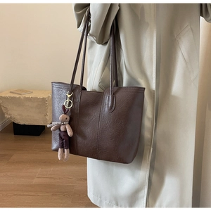 Detail of vintage brown tote bag with textured faux leather and plush rabbit charm