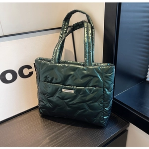 Macro view of dark green quilted tote bag with shiny nylon finish and fashion label