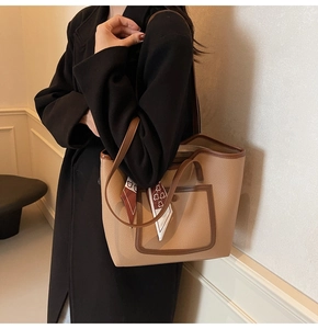 Detail of camel tote bag with lychee texture, outer pocket, and decorative silk scarf