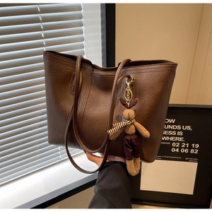 Detail of vintage brown tote bag with wrinkled leather texture and a plush rabbit charm