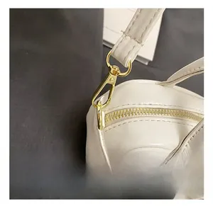 Detail view of premium gold-tone metal hook and neat stitching on white mini bag