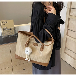 Detailed view of the large capacity canvas tote bag with a cartoon pendant and leather logo