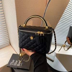 Quilted black bucket bag with gold chain strap and metal handle in lifestyle setting