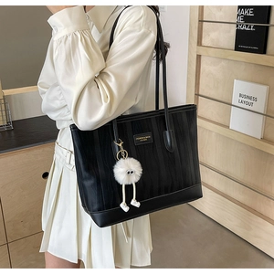 Close-up of black tote bag with vertical stripes texture and cute plush monster charm