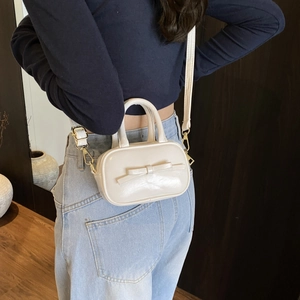 Detailed back view of mini cream crossbody bag with bow worn by child model
