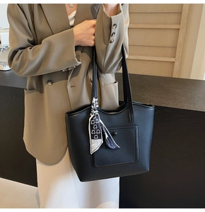 Detail of black textured tote bag with silk scarf and buckle pocket on shoulder