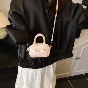 Detail view of a pink mini crossbody bag with bow decoration on a child model