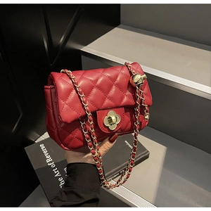 Detail of red quilted bag with gold flower twist lock and adjustable chain strap