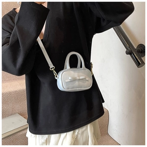 Close-up of mini light blue crossbody bag with bow decoration and gold metal hooks