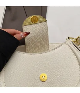 Detail view of cream lychee texture leather handbag with gold magnetic horseshoe buckle