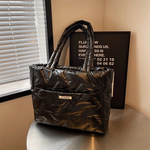 Large black quilted puffer tote bag with V-shaped stitching and fashion label for women