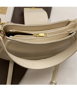 Close-up of beige lychee leather saddle bag interior with golden metal zipper detail